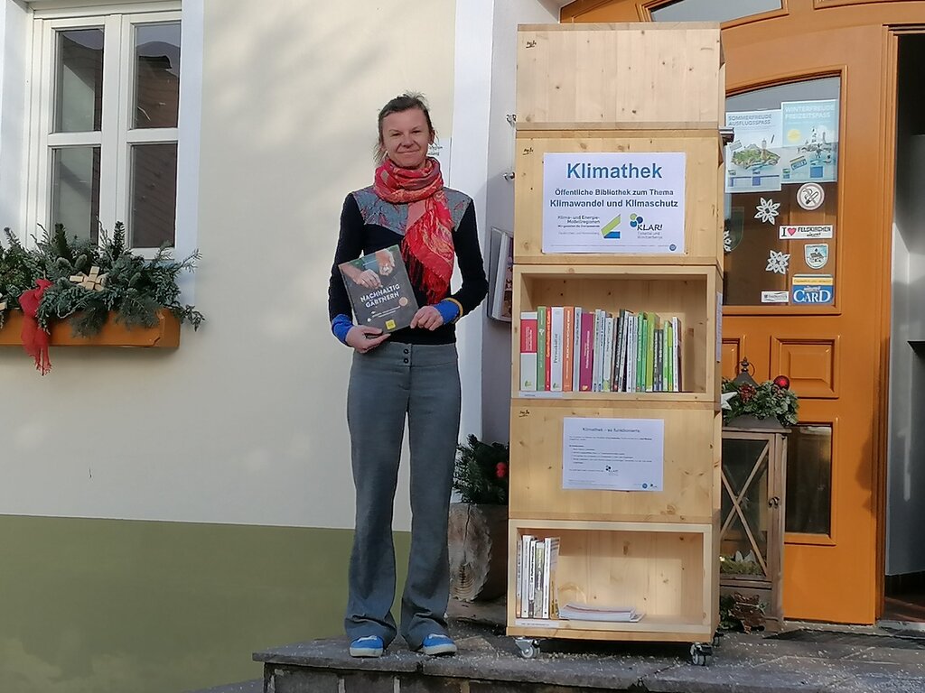 © Verein Fenergiereich Klimathek mit Büchern und links davon Frau mit Buch in der Hand.