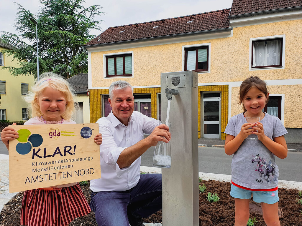 © GDA Amstetten Zwei Mädchen freuen sich mit Landtagsabgeordnetem und Bürgermeister Anton Kasser über den neuen Trinkbrunnen am Kröllendorfer Ortsplatzfer Ortsplatz!