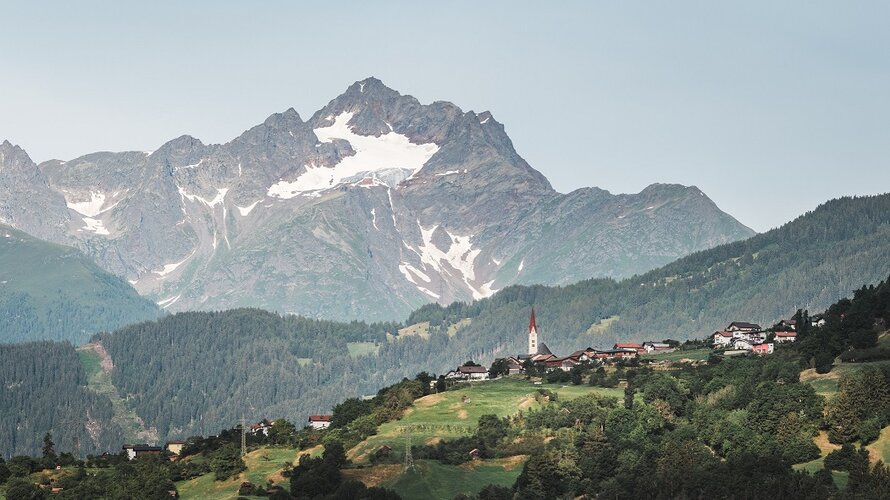 Roman Huber Massive Berge mit Schnee bedeckt und davor Häuser.