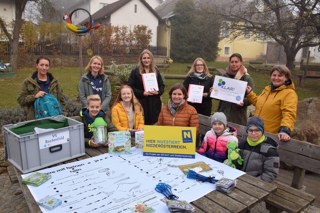 © G. Mayerhofer NÖN Kinder sitzen an einem Tisch und Erwachsene stehen hinter einer Bank.