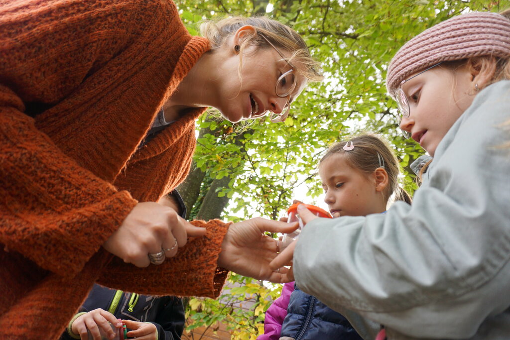 © KLAR! Naturpark Pöllau Eine Frau zeigt Schulkindern etwas.