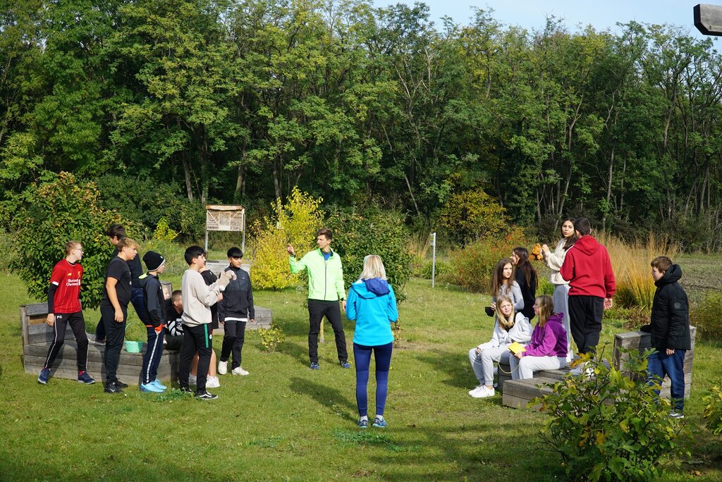 © Gerhard Jungbauer Ein Fitnesstrainer trainiert eine Gruppe von Jugendlichen im Grünen.