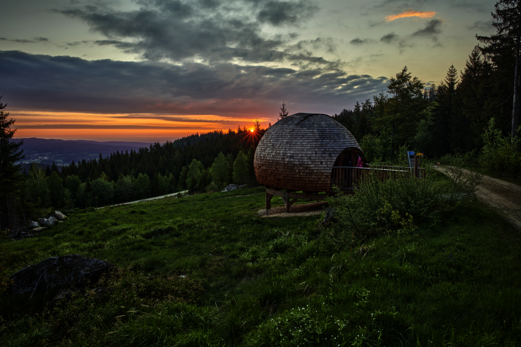 Ausblick vom Berg mit Sonnenuntergang und einer kleinen Hütte am Hang