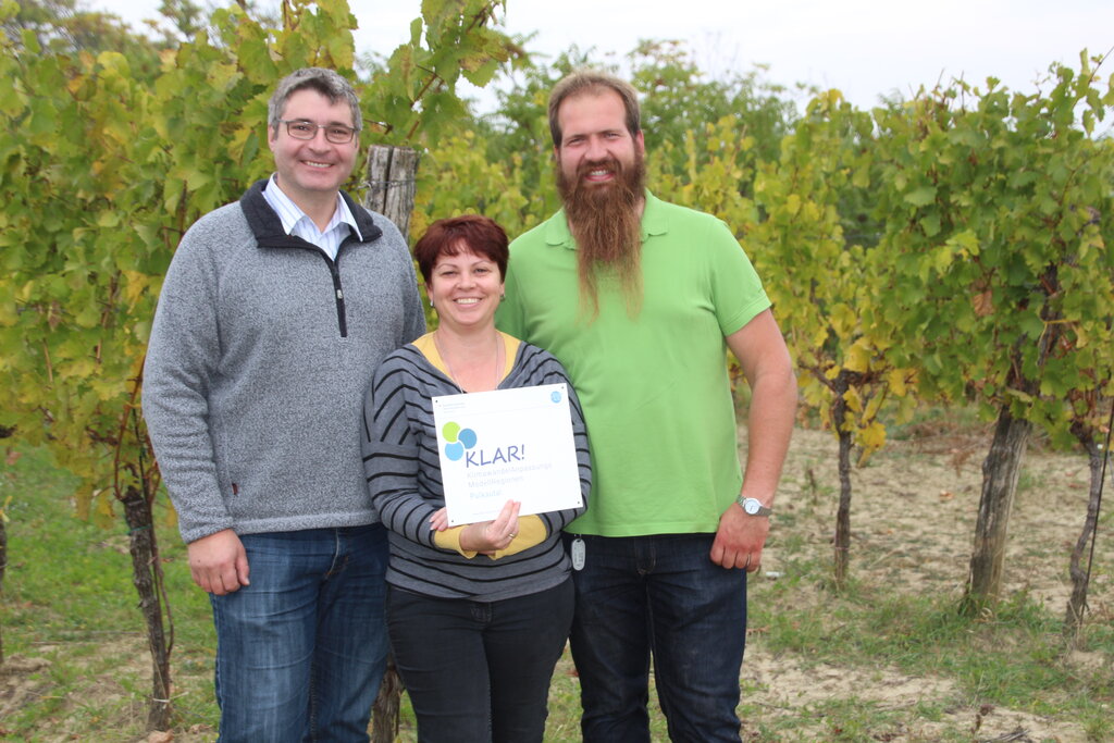 © KLAR!-Pulkautal Drei Personen mit einem KLAR! Schild lächeln in die Kamera
